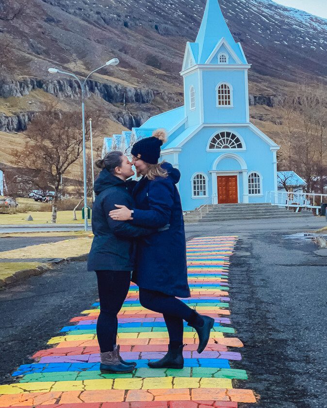 two queer women travelers kissing on rainbow bridge