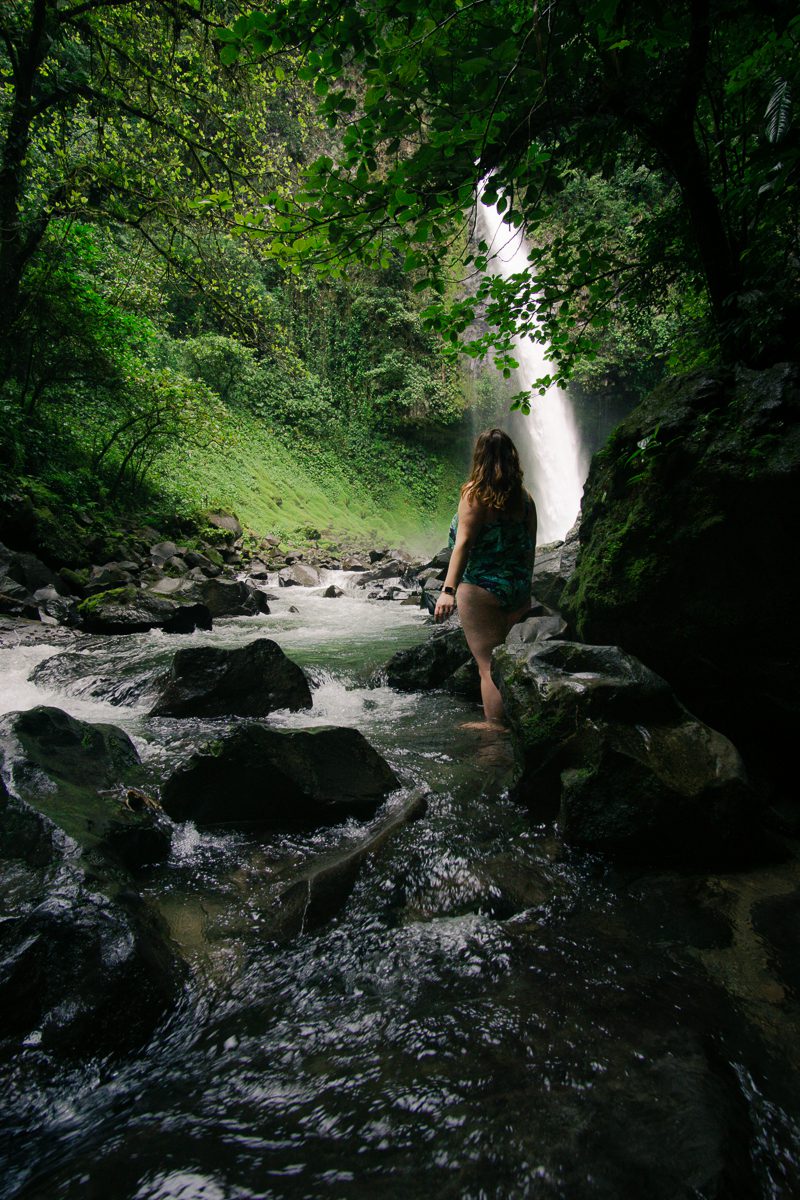 Woman in river at base of La Fortuna waterfall