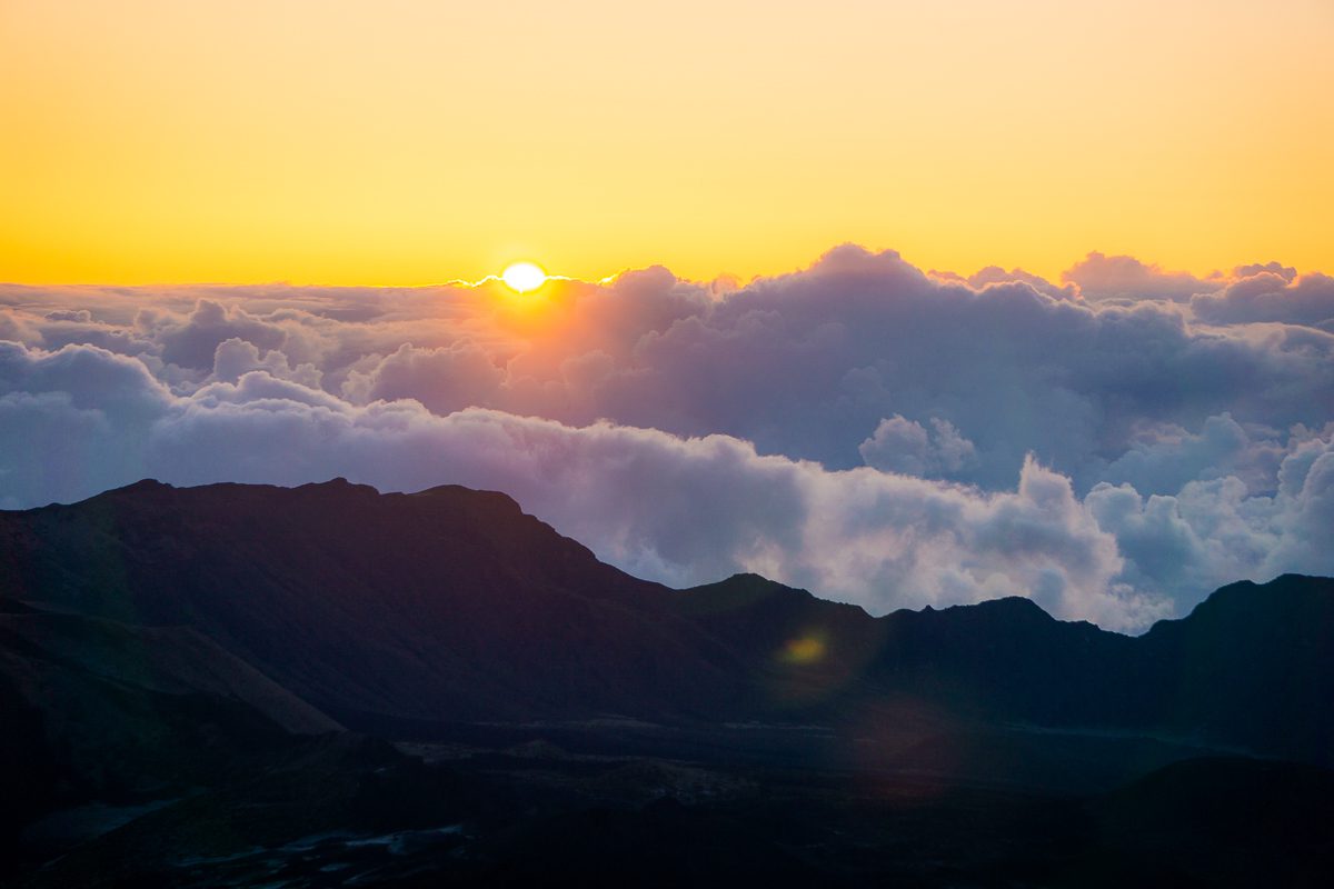 Sun peeking over clouds at sunrise