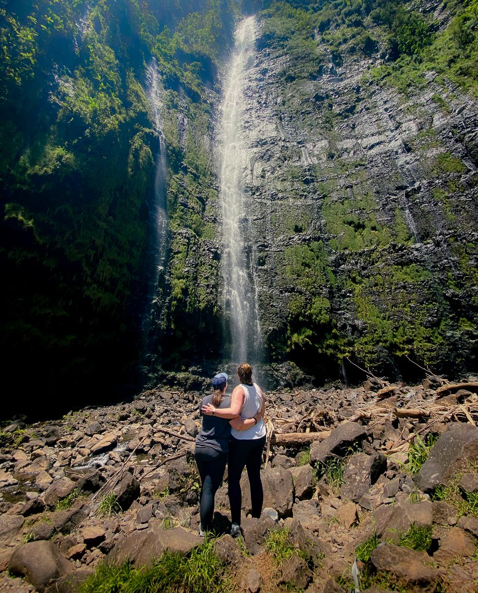 Two women staring up at Waimoku Falls on Maui