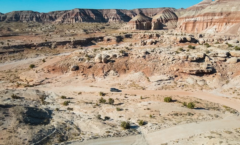 Car in middle of desert on grand circle road trip itinerary